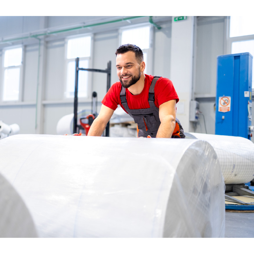 a person rolling a large roll of paper into a printer